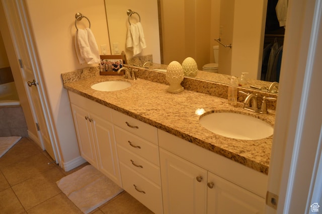 bathroom featuring tile patterned flooring, double vanity, and a walk in closet