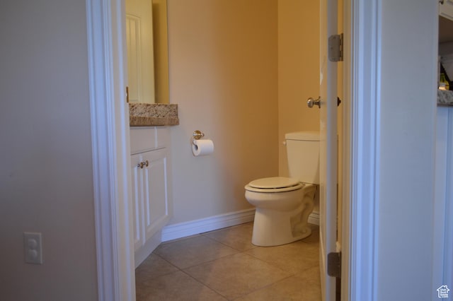 half bathroom with toilet, tile patterned flooring, baseboards, and vanity