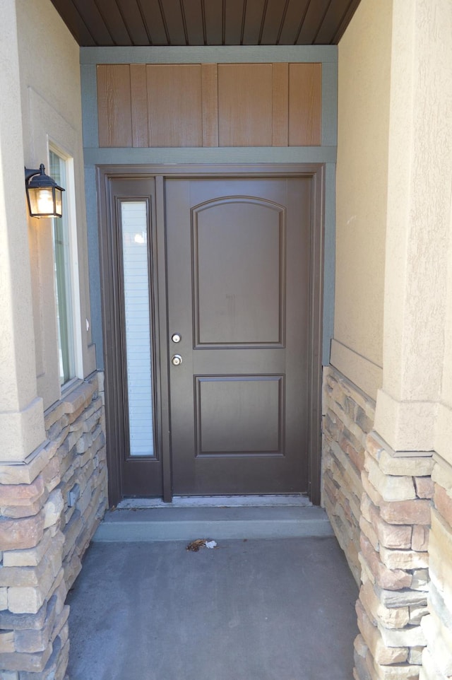 doorway to property featuring stone siding and stucco siding