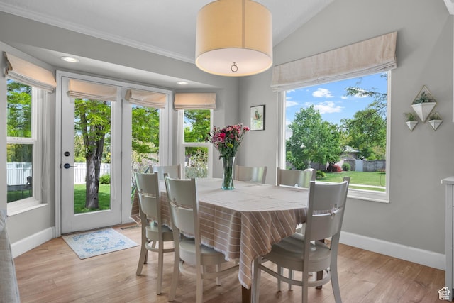 dining room featuring baseboards, light wood finished floors, ornamental molding, and vaulted ceiling