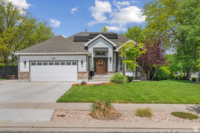 view of front facade with an attached garage, driveway, solar panels, and roof with shingles