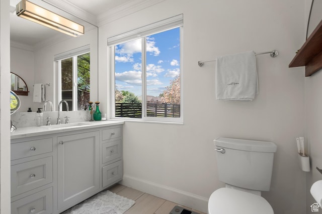 bathroom with baseboards, toilet, crown molding, and vanity