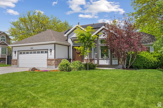 view of front of house with driveway, roof mounted solar panels, an attached garage, a front yard, and brick siding