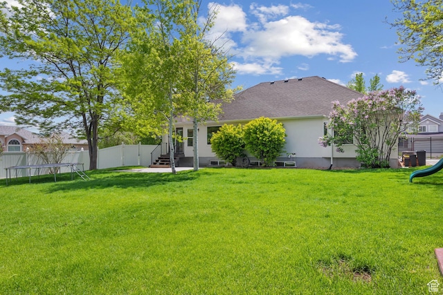 back of property featuring a trampoline, a playground, a shingled roof, entry steps, and stucco siding