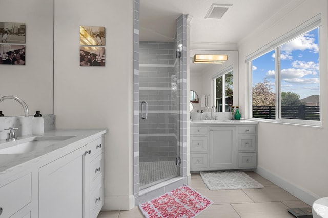 bathroom with a shower stall, crown molding, two vanities, tile patterned floors, and baseboards