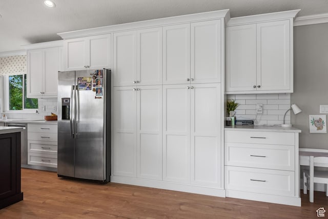 kitchen with stainless steel fridge, light countertops, backsplash, and recessed lighting