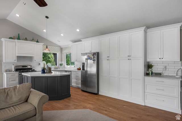 kitchen with appliances with stainless steel finishes, white cabinetry, backsplash, recessed lighting, and lofted ceiling