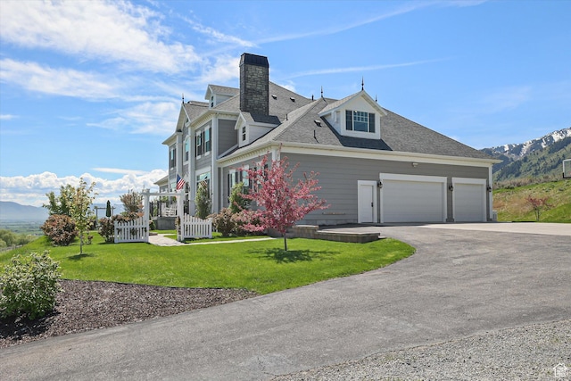 6071 W 1800 S, Mendon, UT 84325 - view of property exterior featuring asphalt driveway, a chimney, a lawn, a garage, and a mountain view