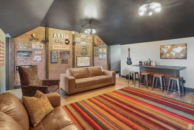 6071 W 1800 S, Mendon, UT 84325 - living area featuring wood finished floors, vaulted ceiling, baseboards, brick wall, and a chandelier