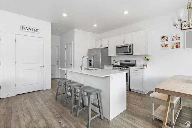 895 S Brubaker Way, Santaquin, UT 84655 - kitchen with appliances with stainless steel finishes, a sink, wood finished floors, a kitchen island with sink, and a breakfast bar