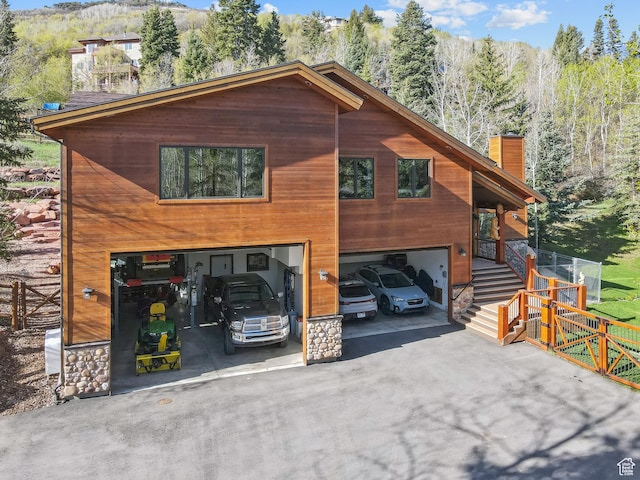 3321 W Big Spruce Way Unit E54, Park City, UT 84098 - view of front of house with a chimney, a garage, asphalt driveway, stairway, and a forest view