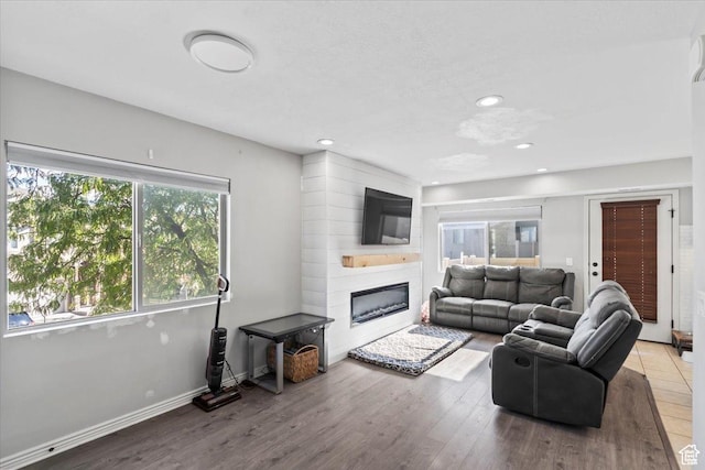 living area featuring a fireplace, wood finished floors, recessed lighting, and baseboards