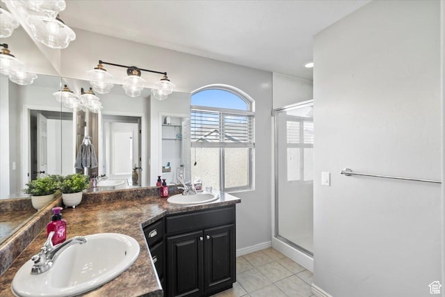 full bathroom with a shower stall, tile patterned flooring, baseboards, and double vanity