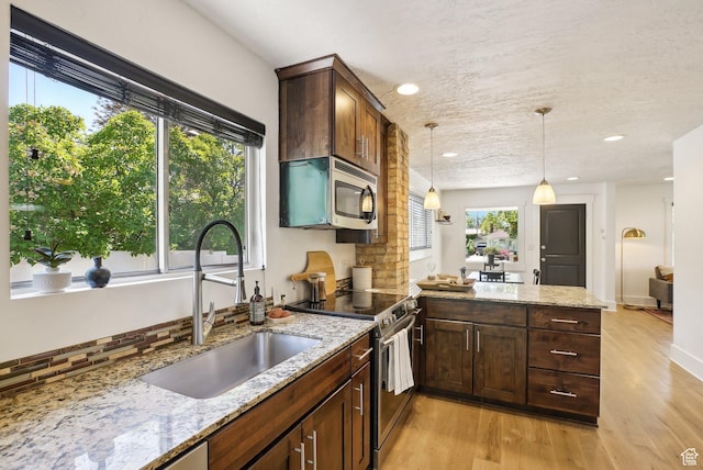 2597 S Elizabeth St, Salt Lake City, UT 84106 - kitchen with appliances with stainless steel finishes, a sink, light wood-style flooring, a peninsula, and healthy amount of natural light