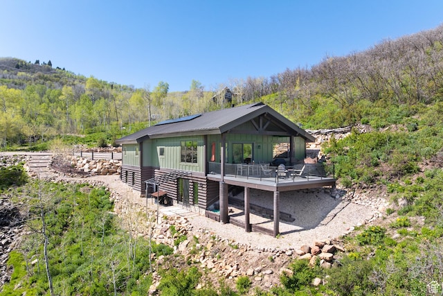 10256 N Basin Canyon Rd, Park City, UT 84098 - back of house with a deck, a view of trees, roof mounted solar panels, and board and batten siding