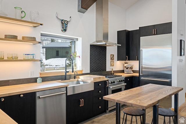 10256 N Basin Canyon Rd, Park City, UT 84098 - kitchen featuring dark cabinetry, wall chimney range hood, high end appliances, a sink, and butcher block countertops