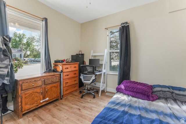bedroom with light wood-style flooring and an office area
