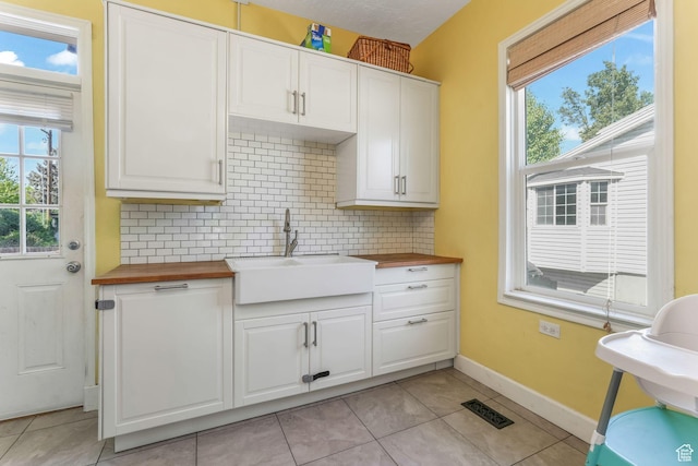 kitchen featuring butcher block counters, a sink, tasteful backsplash, and healthy amount of natural light