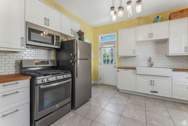 kitchen featuring stainless steel appliances, butcher block countertops, a sink, and white cabinets