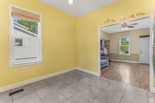 tiled spare room with a ceiling fan and baseboards