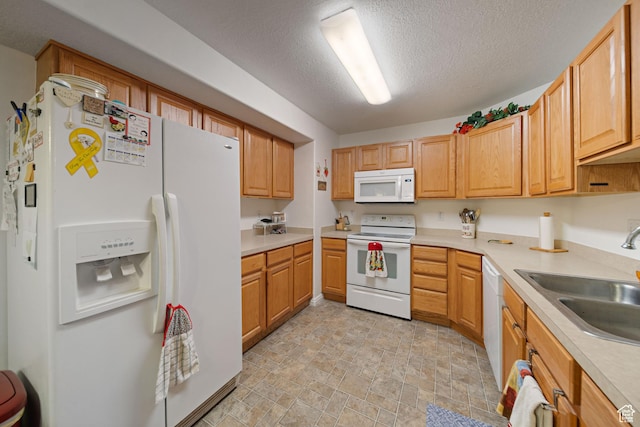 kitchen with white appliances, a sink, stone finish floors, light countertops, and a textured ceiling