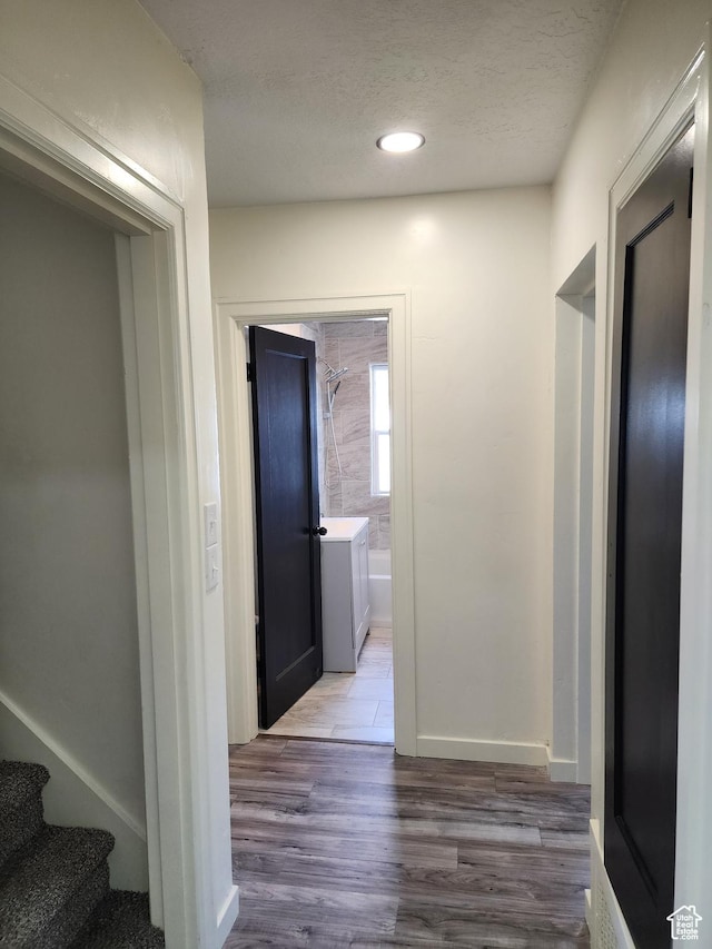 corridor with wood finished floors, a textured ceiling, stairway, and recessed lighting