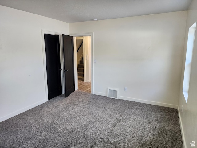carpeted empty room with baseboards and stairs