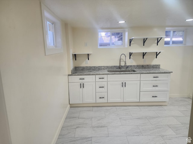 bar featuring a sink, baseboards, and light marble finish flooring
