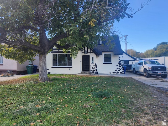 view of front of house featuring stucco siding, a front lawn, and a shingled roof