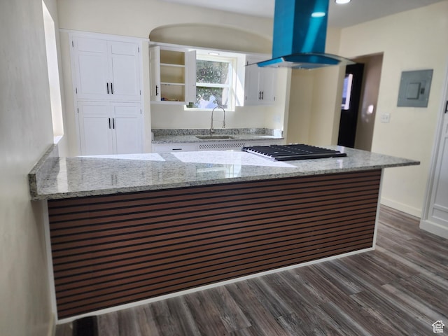 kitchen with stainless steel gas stovetop, island range hood, a sink, white cabinets, and dark wood-style flooring