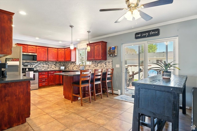 kitchen with stainless steel appliances, dark countertops, reddish brown cabinets, decorative backsplash, and crown molding