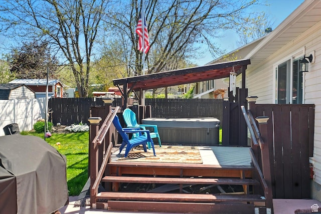 deck with a hot tub, a fenced backyard, and grilling area