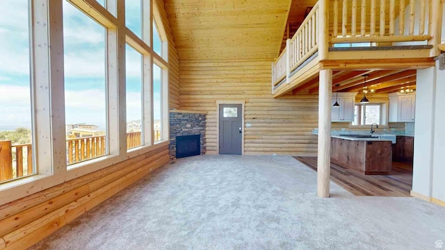 1982 S High Juniper Dr, Cedar City, UT 84720 - unfurnished living room with carpet floors, log walls, high vaulted ceiling, wood ceiling, and a stone fireplace