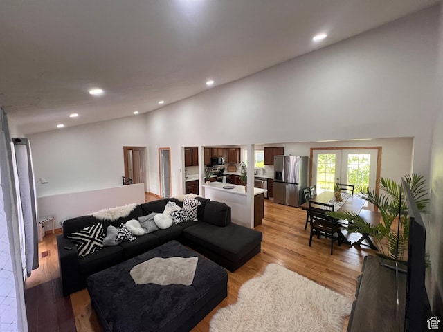 living room featuring high vaulted ceiling, french doors, recessed lighting, and light wood finished floors