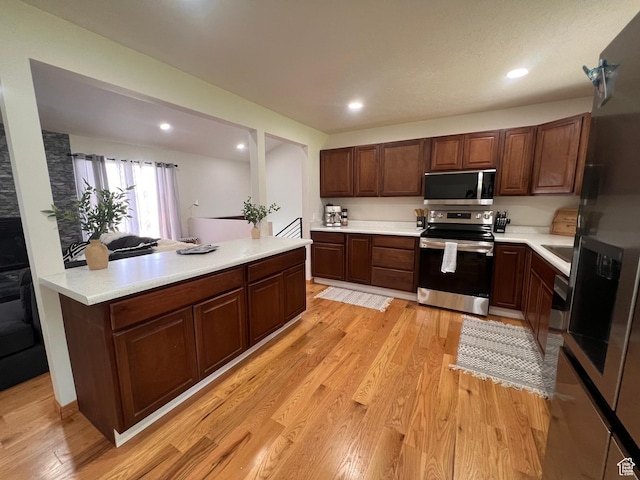kitchen with stainless steel appliances, light countertops, light wood finished floors, and recessed lighting