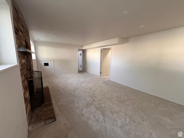 unfurnished living room featuring carpet and a brick fireplace
