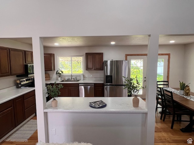 kitchen featuring appliances with stainless steel finishes, a sink, light countertops, light wood-style flooring, and recessed lighting