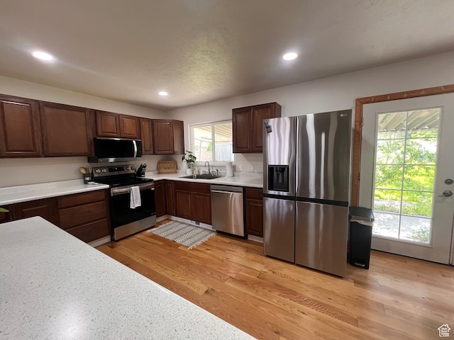 kitchen featuring appliances with stainless steel finishes, light countertops, recessed lighting, a sink, and light wood-type flooring