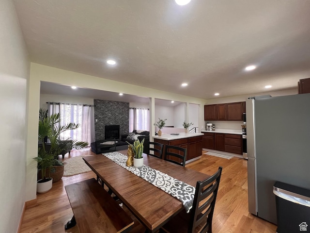 dining space with light wood-type flooring, a fireplace, and recessed lighting