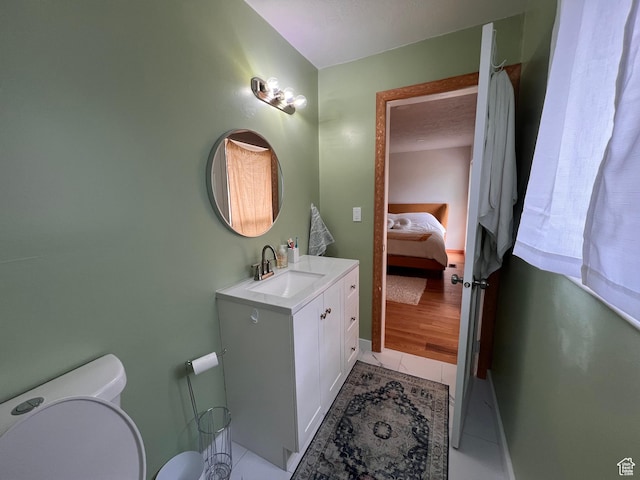ensuite bathroom with toilet, vanity, and baseboards
