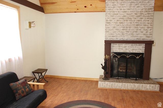 living room featuring lofted ceiling, wood finished floors, baseboards, and a fireplace
