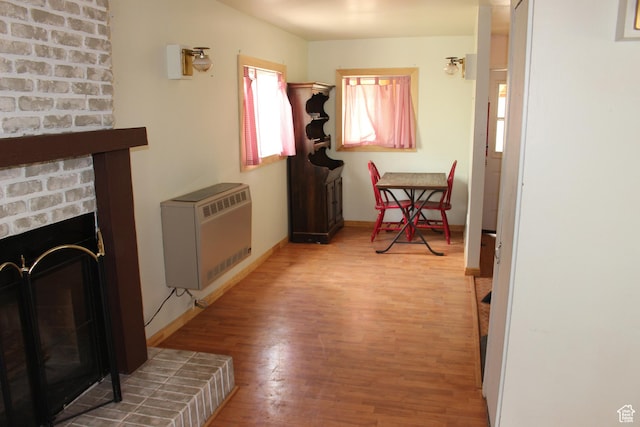 hallway featuring heating unit, wood finished floors, and baseboards