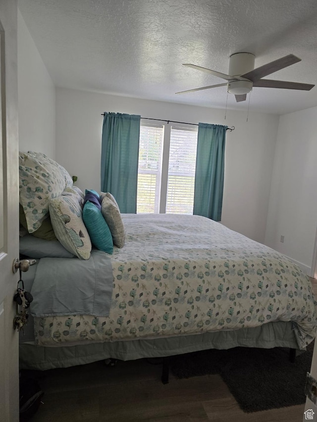 bedroom featuring wood finished floors, ceiling fan, and a textured ceiling