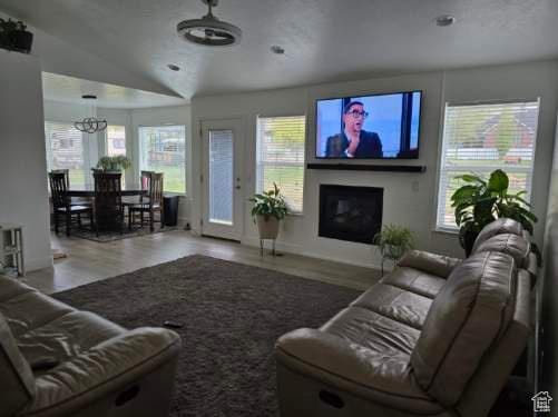 living room with wood finished floors, plenty of natural light, vaulted ceiling, a fireplace, and a chandelier