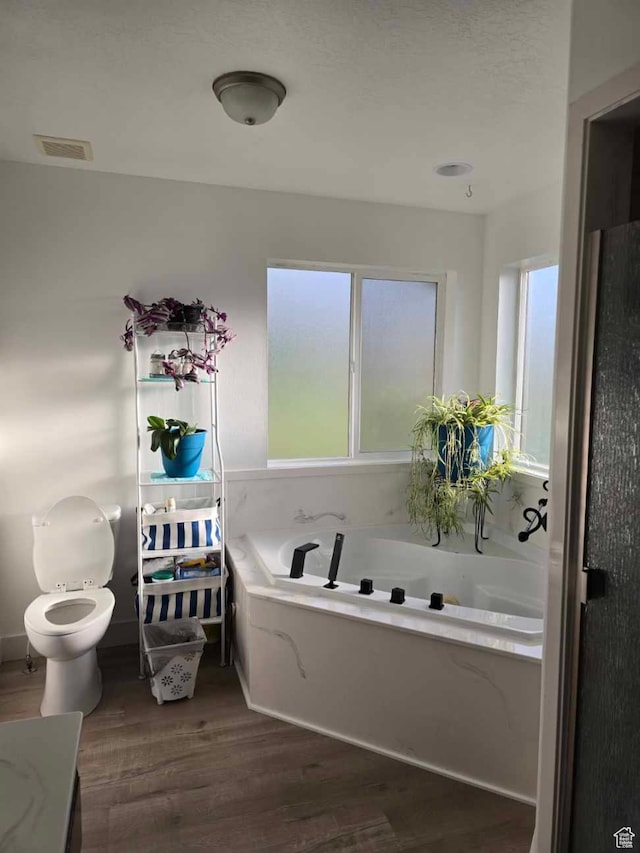 bathroom featuring wood finished floors, a garden tub, and toilet