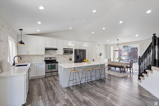 4962 S Glasmann Way S, Ogden, UT 84403 - kitchen with stainless steel appliances, a sink, under cabinet range hood, vaulted ceiling, and a kitchen breakfast bar