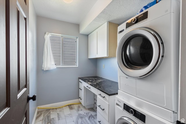 4962 S Glasmann Way S, Ogden, UT 84403 - laundry room featuring stacked washer and clothes dryer, cabinet space, light marble finish floors, and baseboards