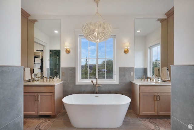 full bathroom featuring a chandelier, a stall shower, two vanities, and a freestanding bath