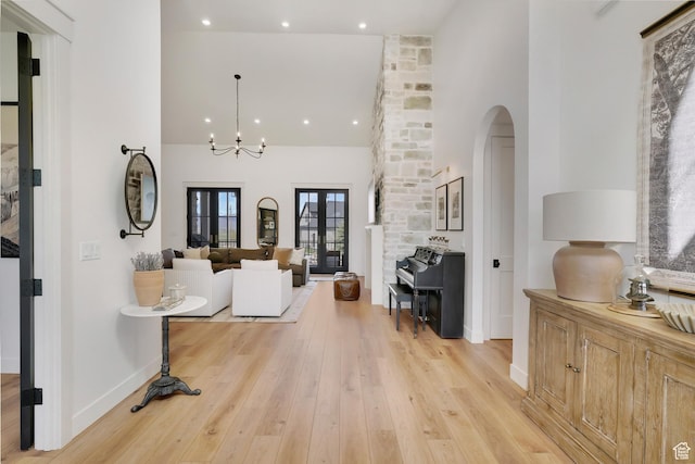 living room featuring high vaulted ceiling, baseboards, light wood finished floors, arched walkways, and recessed lighting