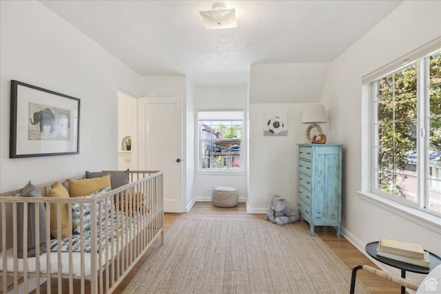 1225 E 700 S, Salt Lake City, UT 84102 - bedroom featuring multiple windows, light wood finished floors, a textured ceiling, and baseboards